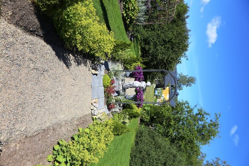 Korkeamäkien puutarhan pääväylä johtaa Lintukodosta Kaukametsään. Portti patsaineen ja istuksineen on rakennettu polulle. Polkua reunustavat jättipoimulehdet (Alchemilla mollis).