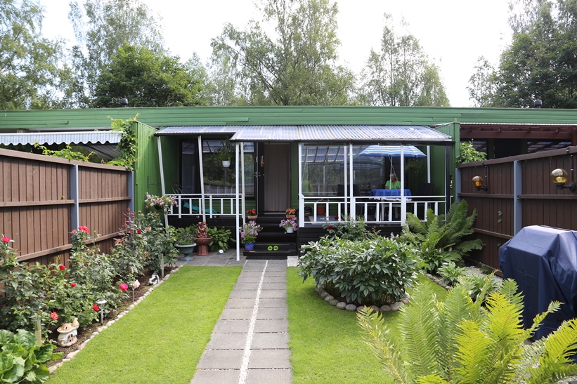 Portilta katsottuna piha jatkuu terassiin ja siitä hyttyssuojan takana olevaan olohuoneeseen. 