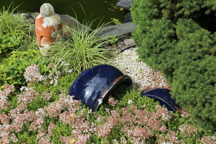 Vesialtaan vieressä oleva patsas ja puoliksi hiekkaan ja valkomaksaruohoon (Sedum album) hautautuneet ruukut häivyttävät kiirettä.